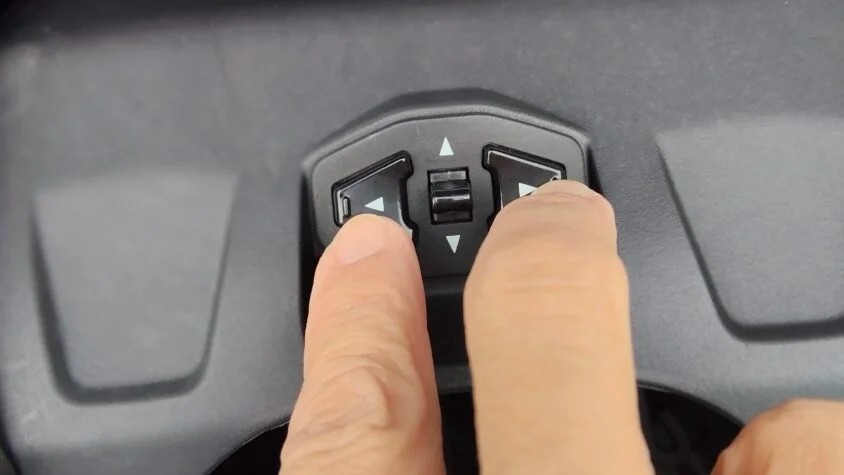 ADV160のメーター下の左右のボタンを指で同時に押しているところ